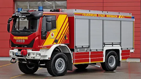 구조·장비 운반차 독일 Miesbach 납품 사진, 앞쪽 비스듬한 모습, 붉은 외벽 앞, 차체에 FEUERWEHR STADT MIESBACH 표기